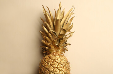 Golden pineapple on beige background, top view. Creative concept