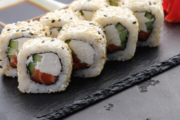Sushi roll with salmon, philadelphia cheese and sesame on plate close up