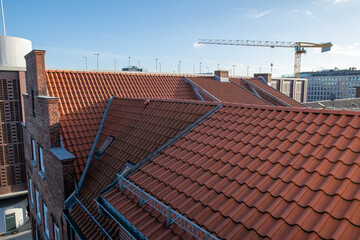Rote dachpfannen D&auml;cher vor blauem Himmel und ein Kran im Hintergrund 
