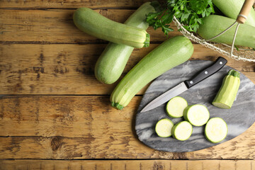 Green ripe zucchinis on wooden table, flat lay. Space for text