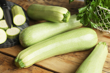 Raw green zucchinis on wooden table, closeup