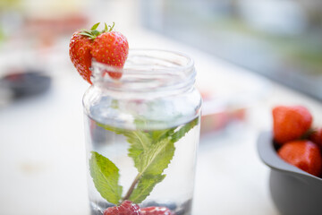 Fototapeta na wymiar Strawberry on the edge of a mint and berries drink