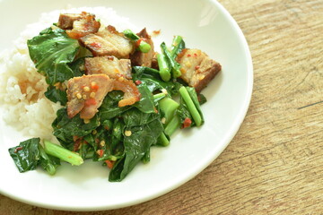 stir fried Chinese kale with crispy pork and rice on plate