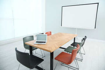 Conference room interior with wooden table and video projection screen