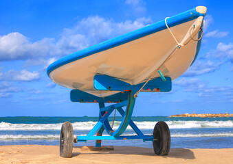 Stand - up paddle boat or hasake stands on a support on a sea beach. Sunny seascape with impressive blue sky and calm blue sea 