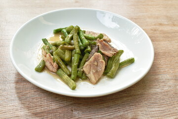 stir fried slice yard long bean with pork on soy sauce on plate