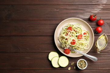 Delicious zucchini pasta with cherry tomatoes served on wooden table, flat lay. Space for text