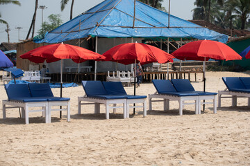 Goa/ India 09 November 2020 Row of covered wooden sun beds with colorful umbrellas on the beach in GOA