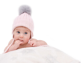 Thoughtful, adorable happy caucasian four-five months baby in winter knitted hat lying on bed, biting finger, isolated on white. Baby care and winter clothes concept. Copy space.