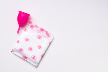 Obraz na płótnie Canvas Menstrual cup and hygienic pad on paper background