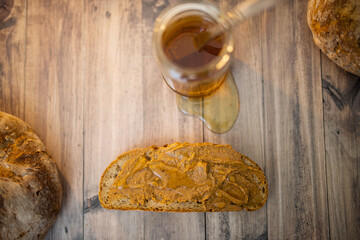 Honey jar and a slice of bread with peanut butter on wooden table
