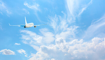 Fototapeta na wymiar White passenger airplane over the clouds - Travel by air transport