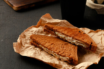 Toasted rye sandwich with ham cut into halves on table