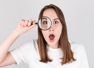 Shocked woman looking through a magnifying glass