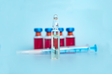 ampoule for vaccination against the background of a syringe with ampoules, on a blue background