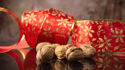 Nuts, details of nuts scattered with Christmas ribbons on a reflective black surface, abstract background, selective focus.