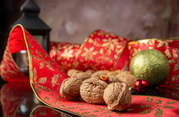 Nuts, details of nuts scattered with Christmas ribbons and lantern on a reflective black surface, abstract background, selective focus.