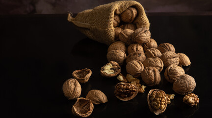 Nuts, walnuts scattered on a reflective black surface, abstract background, selective focus.