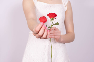 a girl in a white dress holds a red rose in her hand and holds out another