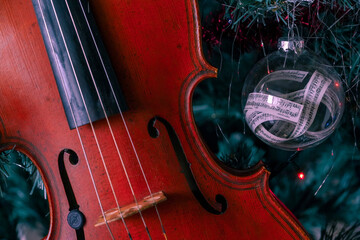 Viola in a Christmas tree next to a decoration ball with a music sheet within  