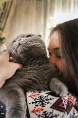 Girl hugging a pet. British cat gray.