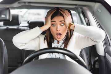  woman holding hands on head while sitting in car and looking at steering wheel