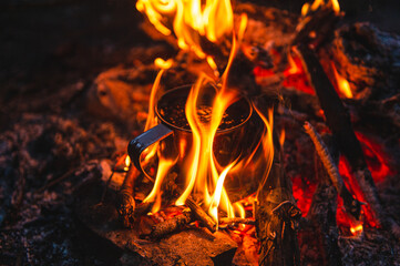 Close up of tea in metal mug heats up in bonfire