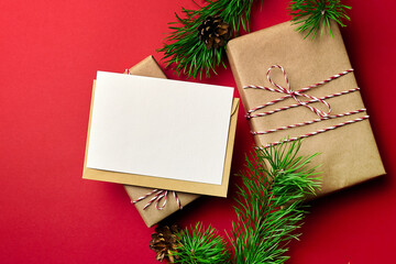 Fototapeta na wymiar Christmas greeting card mockup with gift boxes and pine tree branches on red paper background