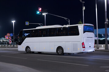 Tourist bus moves at night along street - obrazy, fototapety, plakaty