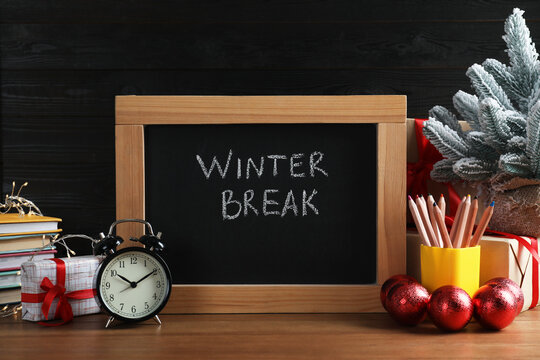Chalkboard with phrase Winter Break, Christmas decor and stationery on wooden table. Holidays concept