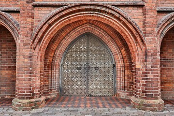 Fototapeta na wymiar Thick metal gates on brick wall