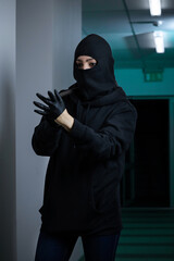 Thief broke into the apartment. House robbery by woman in a black jacket and black mask and crowbar. Burglar in a mask. Thief in a mask trying to break into other people's house	