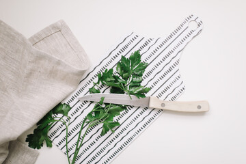 Fresh parsley, greenery with knife and kitchen towel on cutting board isolated on white. fresh healthy meal. Top view, flat lay