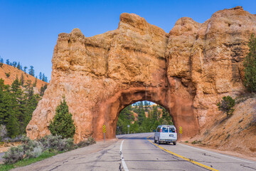 Van passing below an arch sculpted by erosion in Red Canyon, Utah