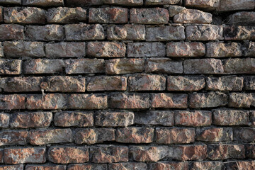 Uneven brick wall with sunlight and shadows, rough and urban wall for a banner, background or texture, no person

