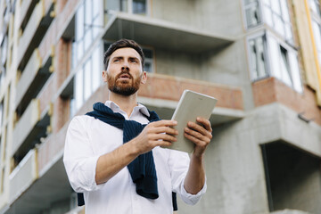 Focused architect using tablet at construction site