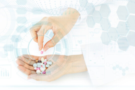 Female fingers picking up a capsule from a medicine handful in abstract scientific backdrop. Concept image for pharmaceutical industry and chemical research.