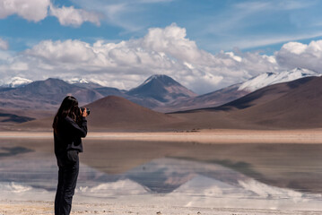 Woman with a camera photographing a volcano in the southwest of the altiplano in Bolivia