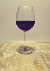  tall transparent glass goblet with dark red wine on a transparent light background