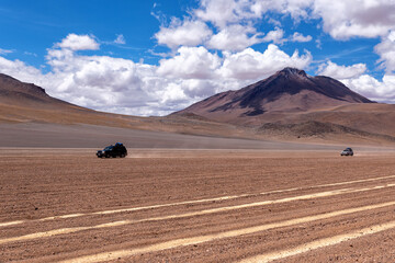 Two cars driving through the southwest of the altiplano in Bolivia in a cloudy day