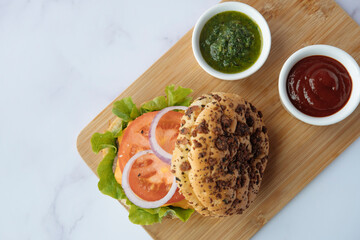 Hamburger. Delicious hamburger with cheese, tomato and vegetables on a wooden board