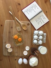 eggs wooden spoon cacao milk and cookbook on the table