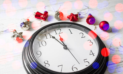 Minute twelve before the New Year. Clock on a white background and Christmas toys.