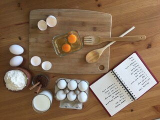 eggs wooden spoon cacao milk and cookbook on the table