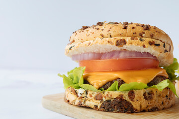 Hamburger. Delicious hamburger with cheese, tomato and vegetables on a wooden board