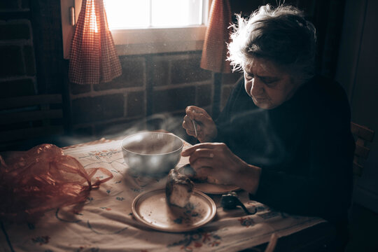 Elderly Woman Sitting Alone At The Table, Eating A Meal