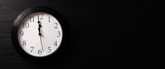 Clock on a black background. A minute to twelve. Banner. Place for your text.