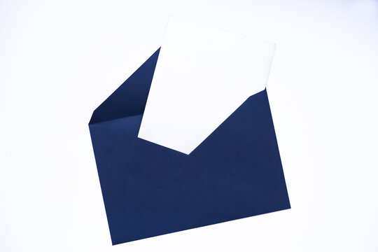 Blank white card peeking from open blue envelope. Minimalist composition on white background. Top view, empty space for text.