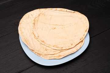 Round pita bread on a dark wooden background.
