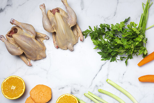 Whole coquelet chickens with raw vegetables ready to cook